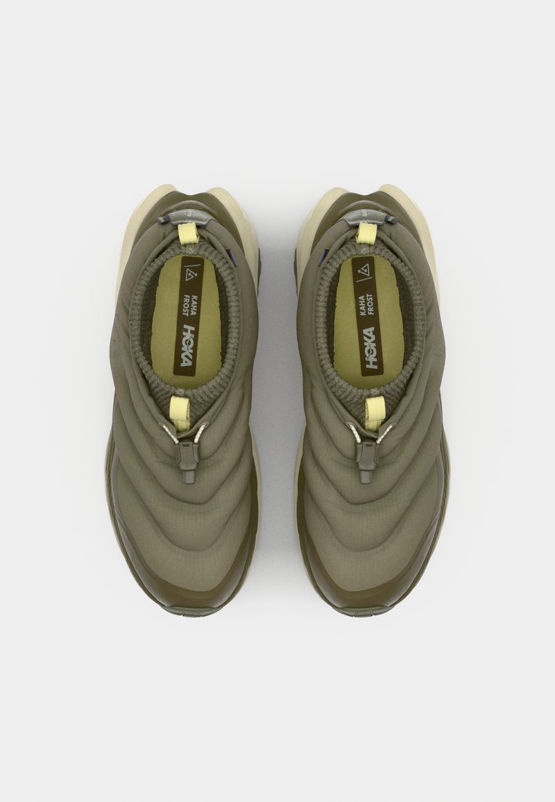 Olijfgroene instappers met een gestructureerd oppervlak, voorzien van een gele accentrits en een gewatteerd zoolontwerp voor comfort en ondersteuning.