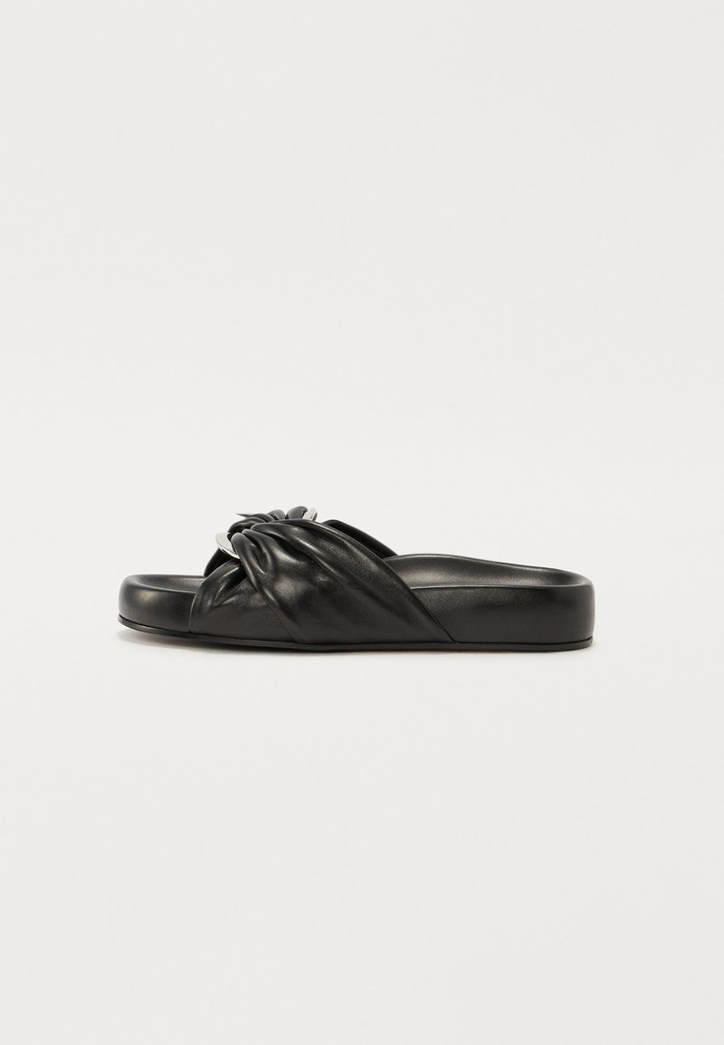 Sandale en cuir noir à glissière avec un design de sangle nouée et une semelle lisse et plate. Bords arrondis et silhouette minimaliste.