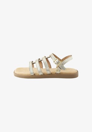 Sandale plata din piele, cu mai multe curele cu margini dințișoare, închidere cu cataramă și un mic talisman în formă de stea pe talpă căptușită bej.