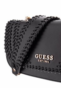 Borsa a tracolla in pelle nera con cuciture decorative e un logo dorato. Presenta una tracolla testurizzata e una chiusura con zip per un accesso facile.