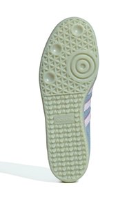 Potplat Adidas tenisice s teksturiranim gripom, kružnim i trokutnim uzorcima, te Adidas logotipom u središtu, dijelom prikazujući plave i ružičaste gornje strane.