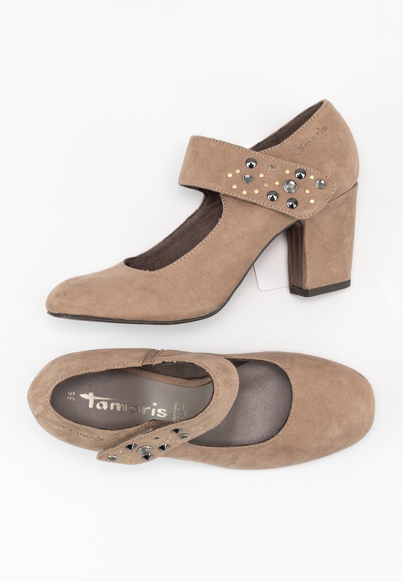 Beige suede high-heeled shoes with a round toe and a strap adorned with black and gold studs. Features a sturdy block heel.