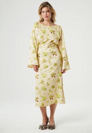 Long-sleeve midi dress in light yellow fabric with a floral pattern in green and brown. Features a matching belt and a slim, A-line silhouette.