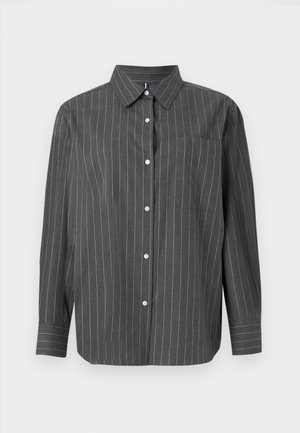 Pilkas ilgomis rankovėmis marškinis su vertikaliomis baltomis juostelėmis, mygtukų užsegimu priekyje, apykakle ir kairiuoju krūtinės kišeniu. Pagamintas iš audinio su lygiu paviršiumi.