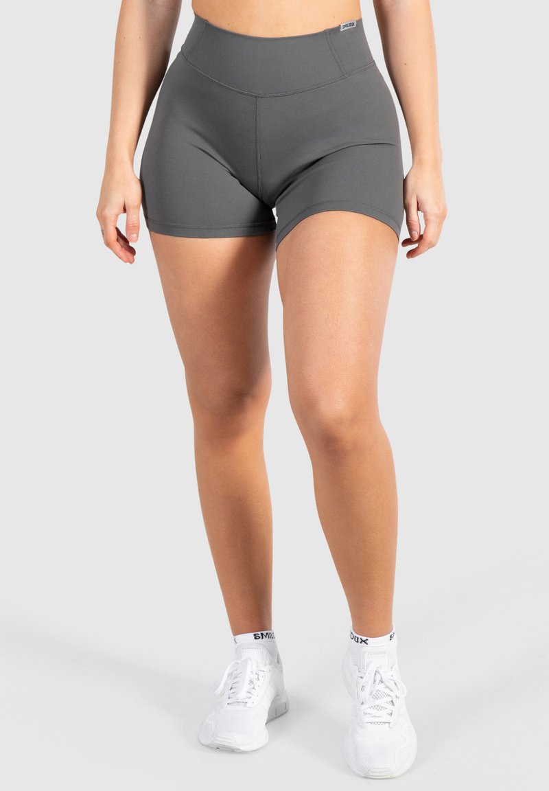 Grijze sportshorts met een hoge tailleband, gemaakt van rekbare stof. Heeft een gladde textuur en minimale stikseldetails. Gepaard met witte sneakers.