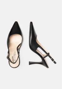 Talons hauts en cuir noir avec une semelle arrière, un bout pointu, un talon effilé et une sangle ajustable à la cheville. L'intérieur est doté d'un revêtement rembourré beige.