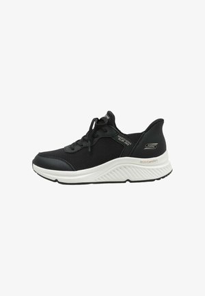 Black athletic shoe featuring a textured mesh upper, rounded toe, white midsole, and black rubber outsole. Laces and branding visible.