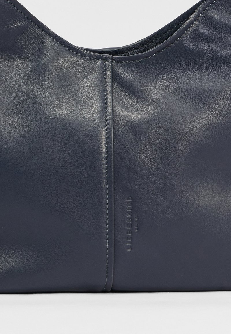 Navyblaue Lederhandtasche mit glatter Textur, abgerundetem oberen Teil und dezentem Nähen. Verfügt über geprägte Markenkennung auf einer Seite.