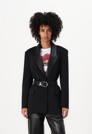 Black blazer with a satin lapel, tailored design, single button closure, two front pockets, and a black belt with a silver buckle.