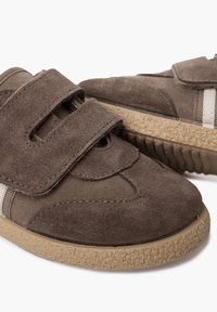 Braune Wildleder- und Nylonschuhe mit zwei Klettverschlüssen, strukturiertem Gummisohle und farblich abgesetzten Streifen in hellerem Farbton an den Seiten.