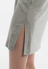 Grijze katoenen jurk met een zijschuifdetail. De stof is zacht met een gladde textuur, met een eenvoudig ontwerp en een relaxte pasvorm.