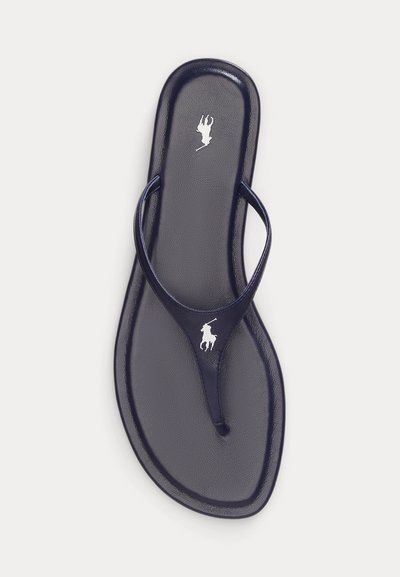 Δερμάτινο σανδάλι τύπου στρινγκ σε ναυτικό μπλε με λευκό λογότυπο παίκτη πόλο στη σόλα και στον ιμάντα, εμφανιζόμενο από πάνω σε λευκό φόντο.