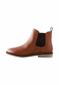 Stivale Chelsea in pelle marrone con pannelli laterali elasticizzati, punta arrotondata e un piccolo passante sul retro. Suola chiara con leggera texture.