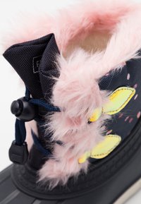 Botte de neige bleu foncé avec garniture en fourrure rose, accents floraux jaunes et œillets de laçage noirs. Semelle en caoutchouc texturée pour une meilleure adhérence.