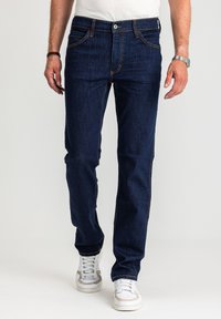 Ciemnoniebieskie dżinsy z denimu o prostych nogawkach, kontrastującym pomarańczowym przeszyciem, pięcioma kieszeniami i zapięciem na guziki.