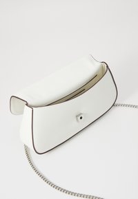 Bela clutch torba od umjetne kože s glatkom teksturom, srebrnim lančićem i kontrastnim tamnim rubom. Ima kopču sa automatskim zatvaranjem i elegantan dizajn.