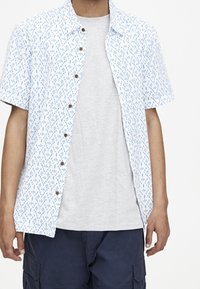 Kortærmet skjorte i hvid bomuld med blåt abstrakt mønster, letvægts, med knaplukning foran og en afslappet pasform. Båret over en grå t-shirt.