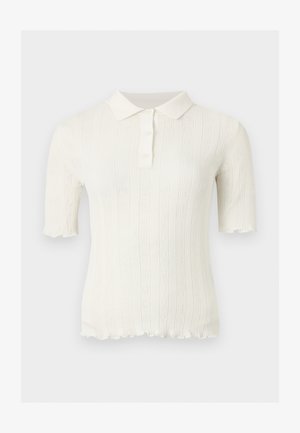 Bijeli pleteni top kratkih rukava s oštrim ovratnikom, prednja ploča sa tri gumba, uspravan rebrasti uzorak i valoviti rubovi na rukavima i donjem dijelu.