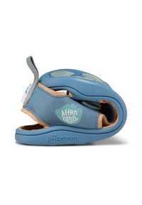 Zapato infantil azul de piel con un interior suave en tono marrón, que presenta un logo en el lateral, forma redondeada y suela flexible.