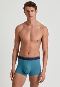 Blauwe geribde boxershorts met een donkerblauwe elastische tailleband waarop het "CALIDA" logo staat. Gemaakt van zachte, rekbare stof voor comfort.