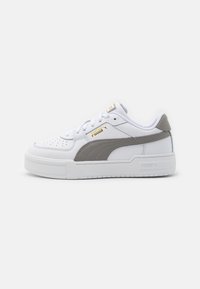Vita lädersneaker med en grå sidostrand, texturerade accenter och en tjock vit gummisula. Har en guldfärgad logotyp på tungan.