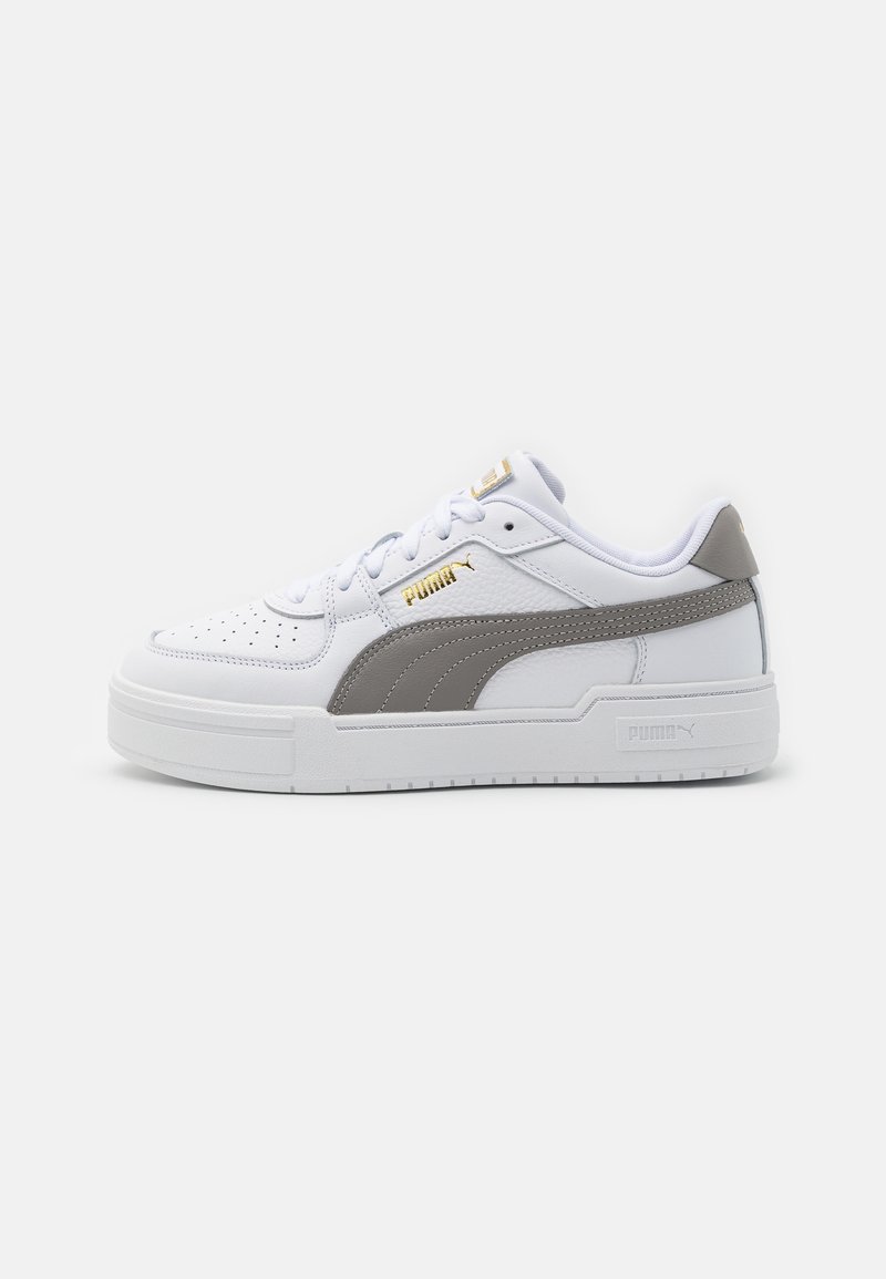Vita lädersneaker med en grå sidostrand, texturerade accenter och en tjock vit gummisula. Har en guldfärgad logotyp på tungan.