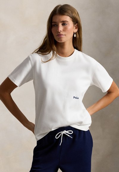 Λευκό βαμβακερό μπλουζάκι με στρογγυλή λαιμόκοψη και κοντά μανίκια. Διαθέτει μικρό μπλε λογότυπο "Polo" κεντημένο στο στήθος.