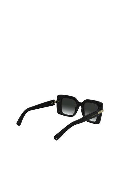 Zwarte vierkante zonnebril met gradient lenzen, dikke monturen en gouden accenten bij de scharnieren. De armen zijn slank en glanzend.