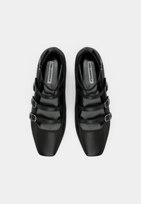 Zapatos de cuero negro con un diseño de punta puntiaguda, que presentan tres hebillas como detalles y una textura lisa. Forro interior visible.