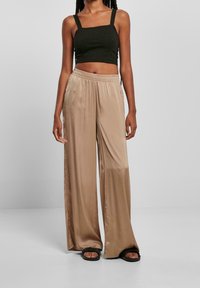 Breda satinbyxor i ljusbeige med elastisk midja. Matchas med en figurnära mörkgrön crop top.