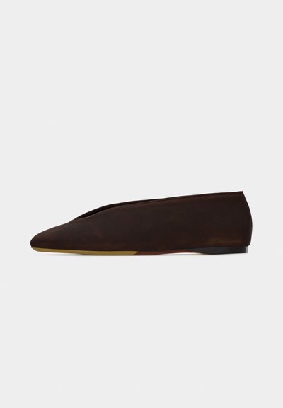 Chaussure plate en daim marron foncé avec un bout pointu et un petit talon, présentée en profil latéral sur un fond blanc.