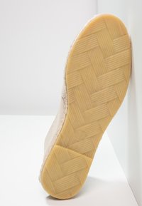 Beige nubukist king, millel on kootud, tekstureeritud kummist tald; külgõmbluse detail ääres toob esile kinga disaini.