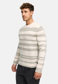 Lett strikket genser i kremhvitt med horisontale grå striper, rund hals og ribbestrikkede mansjetter. Strukturert stoff gir en myk følelse.