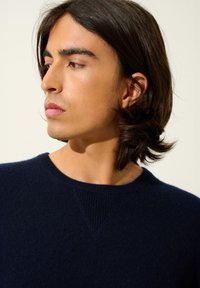 Mörkblå stickad tröja med rund halsringning, med ribbade detaljer vid kragen och ett mjukt, strukturerat tyg.