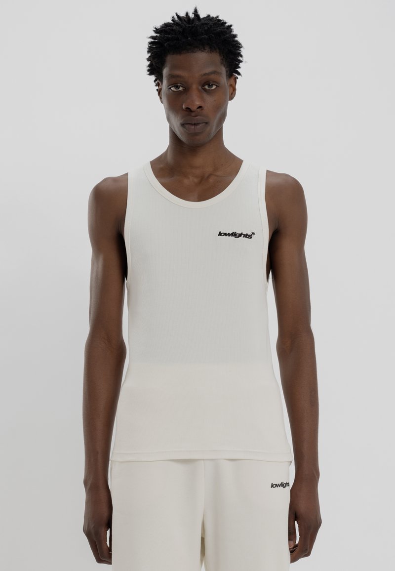 Hvid ribbet tanktop med rund halsudskæring og sort logo på brystet. Lavet af et glat, let stof med en tætsiddende pasform.