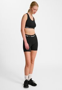Czarny sportowy crop top i szorty, z bandą z logo. Materiał jest gładki i elastyczny, zapewniając dopasowany krój.
