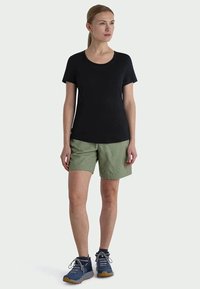 Svart t-skjorte med korte ermer matchet med olivengrønne shorts og marineblå joggesko. Enkel design med avslappet passform og myk stoff.