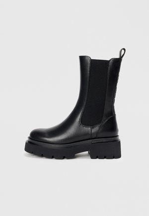 Black leather ankle boot with elastic side panels, round toe, and chunky rubber sole. Smooth texture with minimal design details.