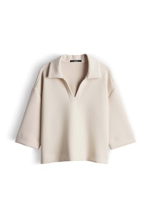 Beiges kurzärmeliges Oberteil mit Kragen und V-Ausschnitt. Hergestellt aus glattem Stoff, mit lockerem Schnitt und leicht abgesenkten Schulternähten.