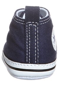 Tmavě modrá plátěná bota s vysokým střihem, zdobená bílým prošíváním, gumovou podrážkou a kruhovým logem na boku.