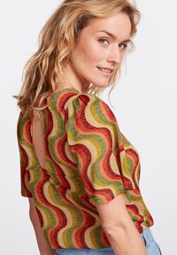 Mehrfarbiges Kurzarmoberteil mit Wellenmuster in Rot, Grün und Gold, mit einem runden Rückendesign und strukturiertem Stoff.