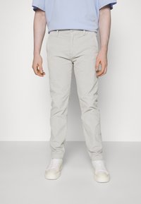 Ljusgrå slim-fit byxor med en strukturerad yta, med en klassisk femficksdesign och knappgylf. Bärs med vita sneakers.