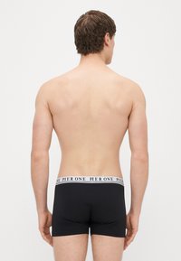 Czarne bokserki z białym elastycznym paskiem w talii oznaczonym napisem "PIER ONE." Materiał wygląda na gładki i dopasowany, widziany od tyłu.