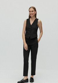 Svart väst- och byxset med silverrand, som har V-ringning, fem knappar och en slimmad, skräddarsydd passform. Glansiga svarta loafers fulländar looken.