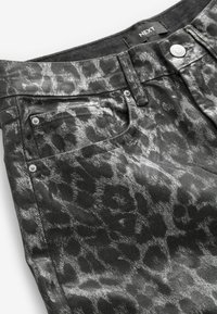 Schwarze Denim-Jeans mit einem metallischen Leopardenmuster, im klassischen Fünf-Taschen-Stil und mit Metallakzenten.