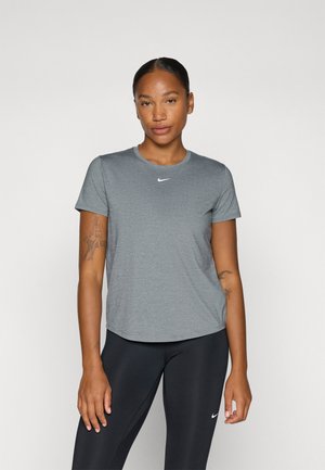 Grå atletisk t-shirt med korta ärmar, rund halsringning och en vit Nike-logga centrerad på bröstet. Bärs tillsammans med svarta leggings.