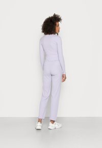 Pijama de duas peças riscado em lavanda e branco. Top de mangas longas e calças justas com bainhas arredondadas. Material de algodão macio.