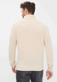 Maglione beige a maglia con collo alto, polsini e orlo a coste. Presenta una texture morbida ed è realizzato per una vestibilità comoda.