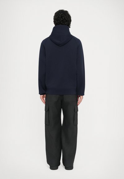 Μπλε σκούρο φούτερ με κουκούλα, άνετη εφαρμογή, παχύ υλικό και ριμπ τελείωμα. Συνδυασμένο με άνετο μαύρο cargo παντελόνι με πολλές τσέπες.