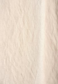 Helle Beige, strukturierte Stoff mit einem subtilen, ungleichmäßigen Muster. Die Oberfläche wirkt leicht zerknittert und besteht aus natürlichen Fasern.